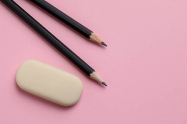 Pembe arka planda silgi ve kalemler, düz yatış. Metin için boşluk