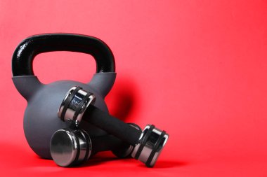 Kırmızı arka planda kettlebell ve dambıllar. Metin için boşluk