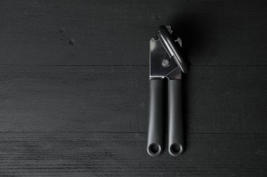 Siyah ahşap masada bir konserve açacağı, üst manzara. Metin için boşluk