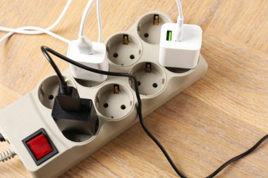 USB adaptörleri ve elektrik kabloları tahta masanın üzerinde, görüş açısının üstünde.