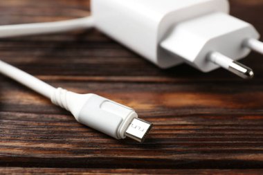 Tahta masada şarj kablosu olan USB güç adaptörü, yakın plan.