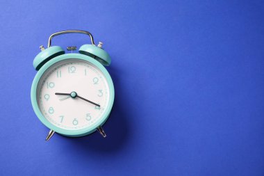 Mavi arka planda bir turkuaz alarm saati, üst manzara. Metin için boşluk