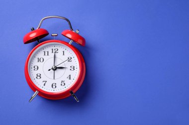 Mavi arka planda bir kırmızı alarm saati, üst manzara. Metin için boşluk