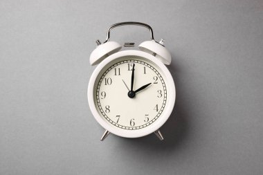 Açık gri arkaplanda bir beyaz alarm saati, üst görünüm