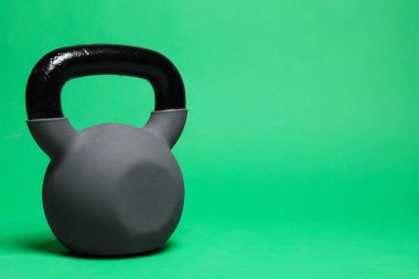 Yeşil arka planda ağır bir kettlebell, yakın plan. Metin için boşluk