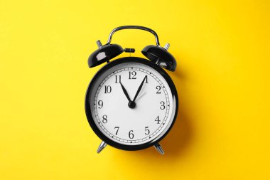 Sarı zemin üzerinde siyah alarm saati, üst görünüm