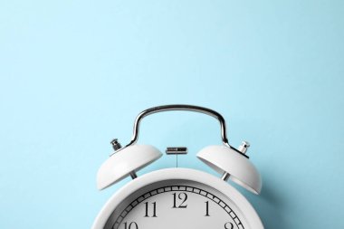 Açık mavi arka planda beyaz alarmlı saat, üst manzara. Metin için boşluk