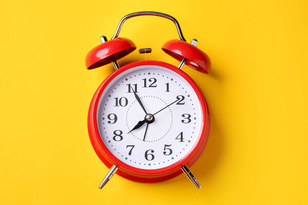 Красный будильник на желтом фоне, вид сверху