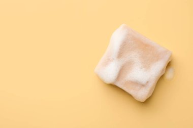 Sarı arka planda köpüklü sabun çubuğu, üst manzara. Metin için boşluk