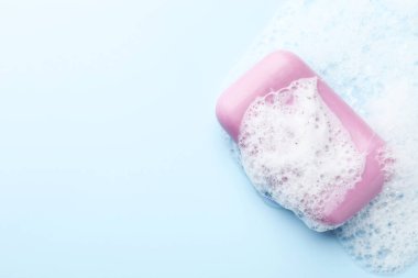 Açık mavi arka planda köpüklü sabun çubuğu, üst manzara. Metin için boşluk
