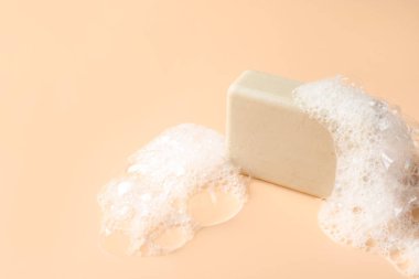 Bej arka planda köpük olan sabun çubuğu, yakın plan. Metin için boşluk