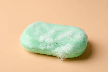 Bej arka planda köpük olan sabun çubuğu, yakın plan.