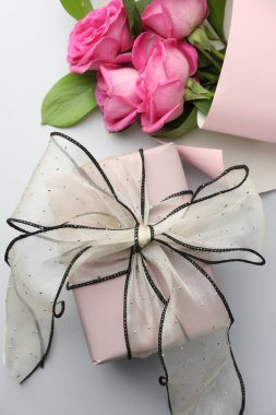 Güzel bir fiyonk ve pembe güllerle donatılmış bir hediye kutusu.