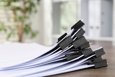 Kapalı alanda, ahşap masa üzerinde kağıt kağıtları olan ataçlar.