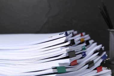 Koyu arkaplan üzerinde kağıt kağıtları olan renkli cilt ataçları, yakın plan