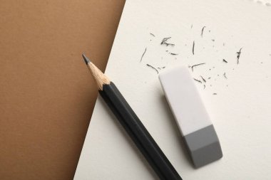 Silgi, kalem, kırıntılar ve kahverengi arka planda defter, üst manzara. Metin için boşluk