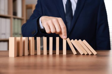 Ahşap blokların masada düşmesini engelleyen adam, yakın plan. Domino etkisi