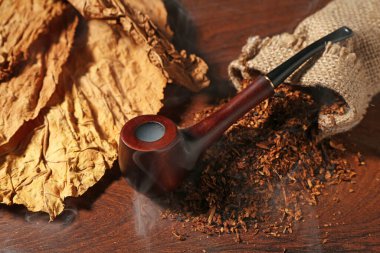 Tütün, kurumuş yapraklar ve sigara piposu ahşap masada, yakın plan.