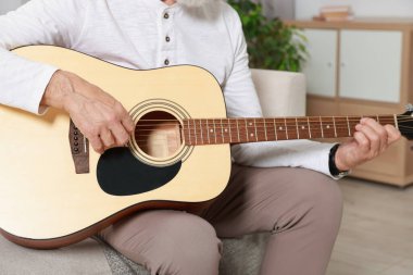 Rahatlatıcı hobi. Son sınıf öğrencisi evdeki kanepede gitar çalıyor, yakın plan.