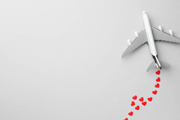 Plane model and paper hearts on grey background, flat lay. Space for text