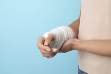 Bileğinde bandaj olan kadın açık mavi arka planda, yakın plan.