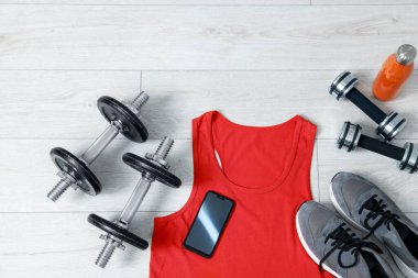 Spor atlet, akıllı telefon ve spor aletleri yerde, düz yatıyordu.