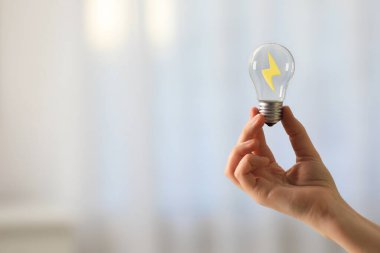 Arka plan bulanık, içinde yıldırım olan ampulü tutan kadın, yakın plan. Fikir, girişim, yenilik, yaratıcılık ve enerji verimliliği kavramları