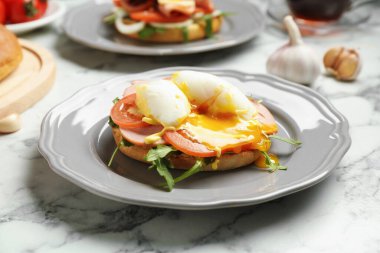 Lezzetli bir kahvaltı. Haşlanmış yumurta, jambon, domates, roka ve ekmek beyaz mermer masada, yakın plan.