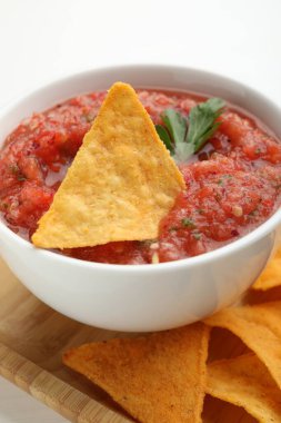 Lezzetli baharatlı salsa sosu, beyaz masada nacho cipsi, yakın plan.