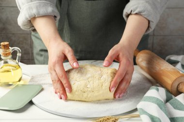 Beyaz ahşap masada hamur yoğuran kadın, yakın plan.