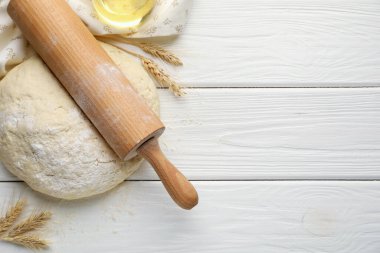 Taze hamur, merdane, yağ ve çiviler beyaz ahşap masada, düz yerde. Metin için boşluk