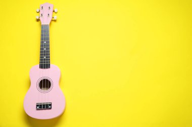 Sarı arka planda bir ukulele, üst manzara. Metin için boşluk