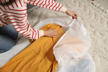 Kadın giysi örtüsüne bürünüyor. Evin içinde, manzaranın üstünde.