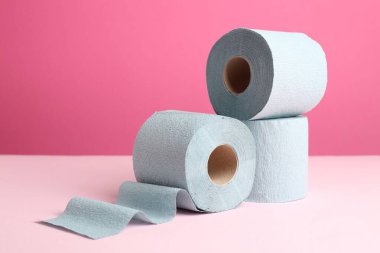 Pembe arka planda mavi tuvalet kağıdı ruloları. Metin için boşluk
