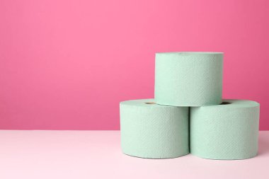 Pembe arka planda yeşil tuvalet kağıdı ruloları. Metin için boşluk