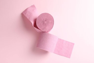 Açık pembe arka planda renkli tuvalet kağıdı ruloları, üst görünüm