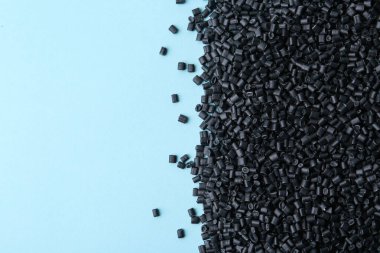 Açık mavi zemin üzerinde siyah plastik granüller yığını, üst manzara. Metin için boşluk