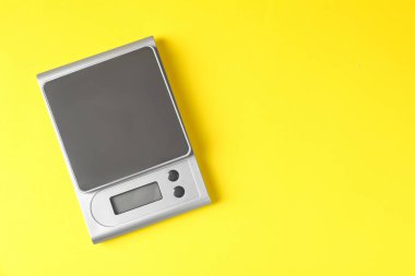 Sarı arka planda modern elektronik mutfak terazisi, üst manzara. Metin için boşluk