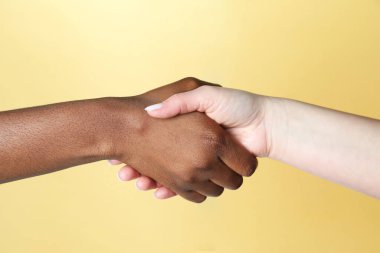 Irkçılığı bırak. Farklı ten renginde insanlar bej arka planda el sıkışıyor, yakın plan