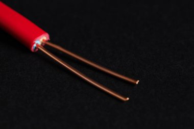 Siyah arkaplanda kırmızı şeritli elektrik kablosu, yakın plan.