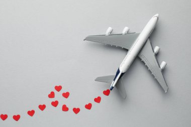 Uçak modeli ve kağıt kalpler gri arka planda, düz yatıyordu