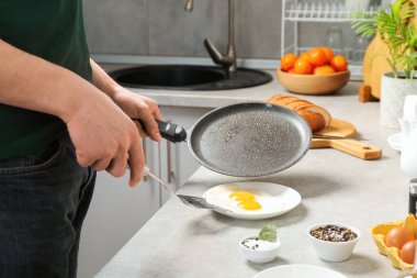 Kızartma tavalı olan adam mutfaktaki tabağa lezzetli yumurta koyuyor, yakın plan.