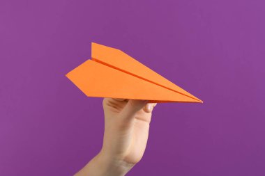 Mor arka planda turuncu kağıt uçaklı kadın, yakın plan.