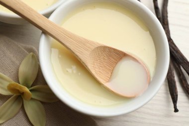 Lezzetli vanilyalı yoğunlaştırılmış sütü kaseden kaşıkla beyaz ahşap masaya alıp, düz bir şekilde yatıyordu.