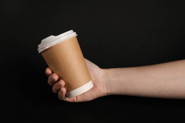 Siyah arka planda kağıt bardak tutan kadın, yakın plan. Tasarım için model