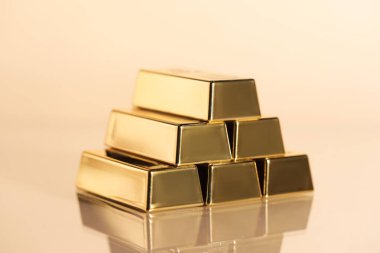 Birçok üst üste dizilmiş altın çubuklar bej arka planda, yakın plan