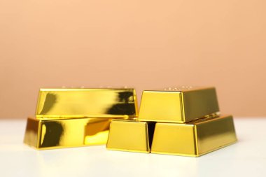 Parlak altın çubuklar beyaz masa üzerinde bej arka plan, yakın plan