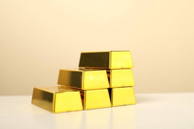 Bej arkaplan ile aydınlık masa üzerindeki altın külçeleri, yakın plan