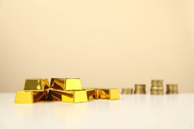 Bej arka plan ve seçici odak karşısında altın külçeler ve sikkeler