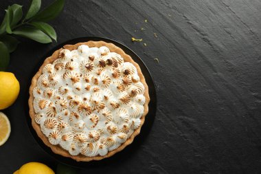 Lezzetli kremalı turta ve siyah desenli masada limonlar. Metin için boşluk